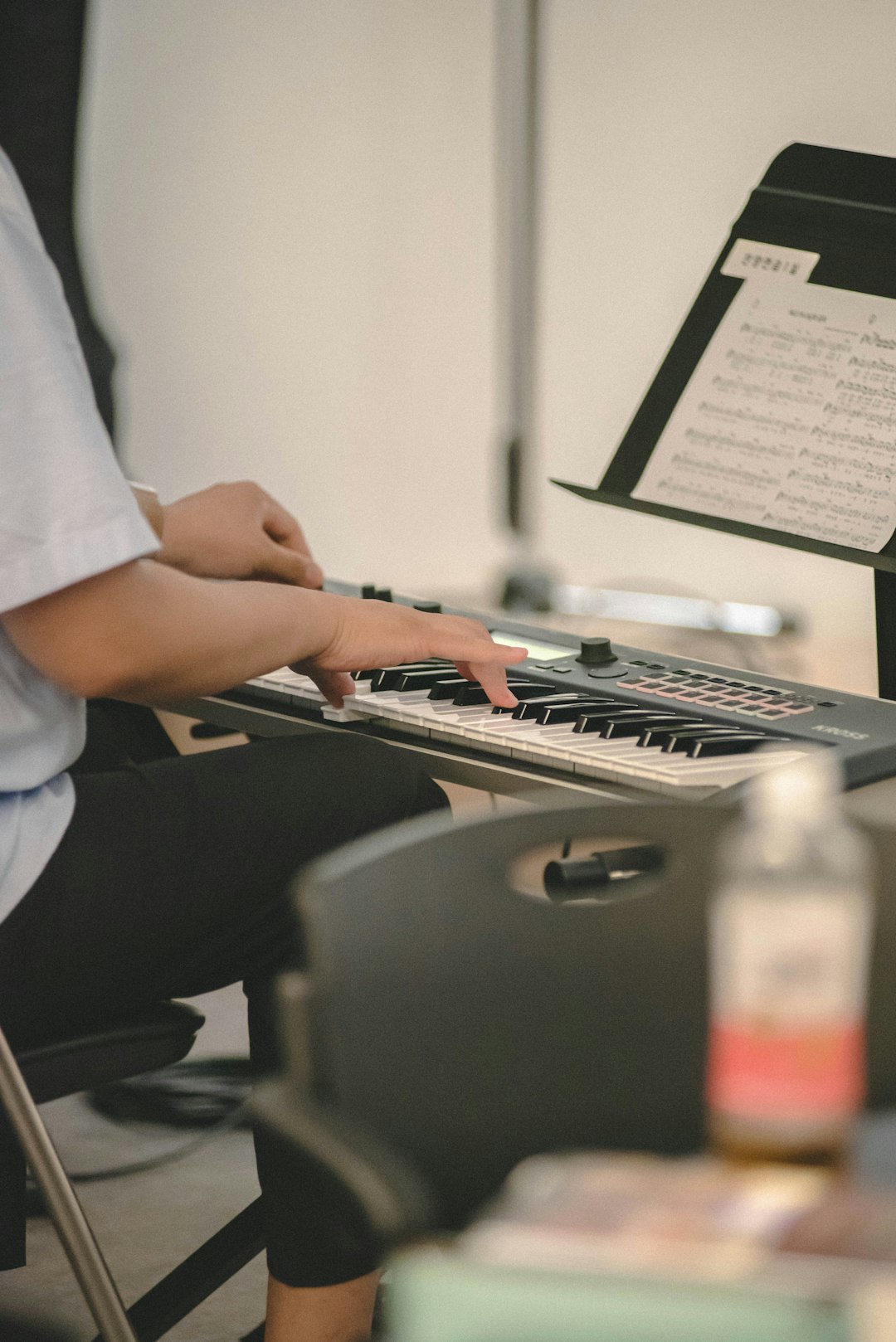 person-playing-a-digital-piano-with-sheet-music-0c6p-7wmqw8
